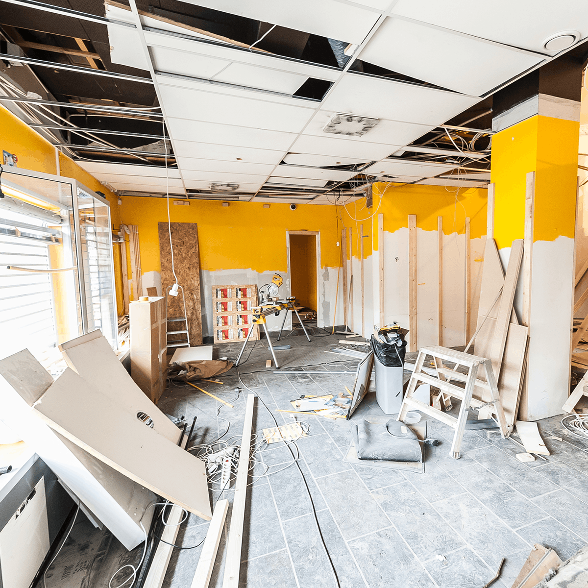 Binnenruimte huis volledig in renovatie met bouwmaterialen, gereedschap en halfopen plafond.