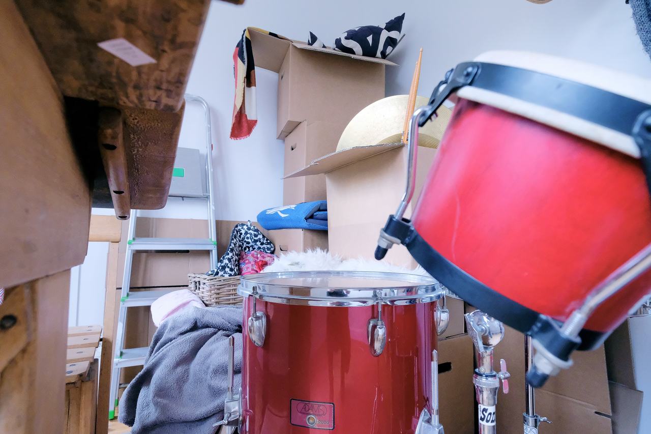 Close up of a drum kit with all kinds of hobby-related gear in the background