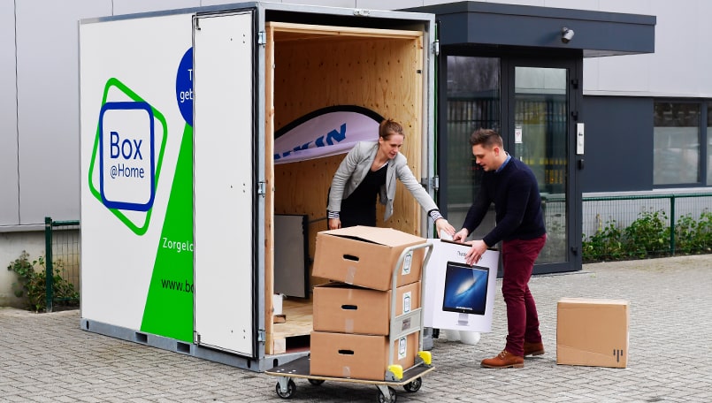 Twee collega's laden de inboedel van hun kantoor in een Large Box van Box@Home